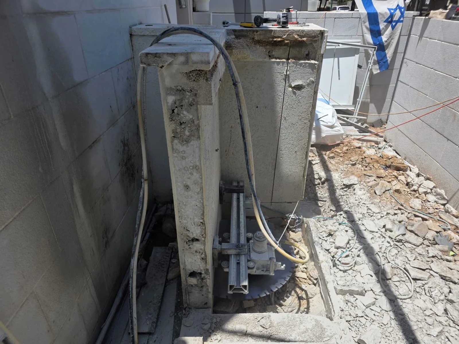 מסור קיר על מסילה ליד אלמנט בטון בחצר פרטית בנתניה